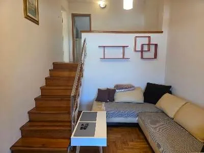 Living room with a sofa and stairs leading to the upper level. - image 7