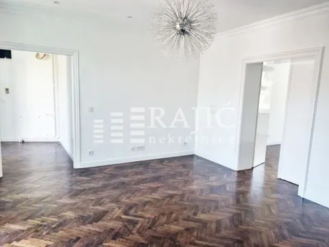Empty bright room with dark parquet flooring and a decorative chandelier. - image 4