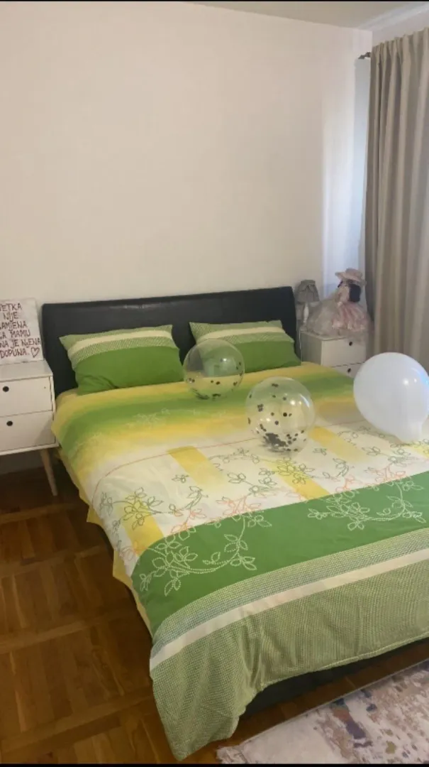 Svijetla spavaća soba sa bračnim krevetom i noćnim stočićima.