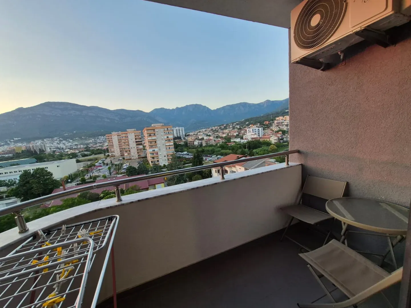 Namješten balkon sa garniturom za sjedenje i pogledom na grad i planine.