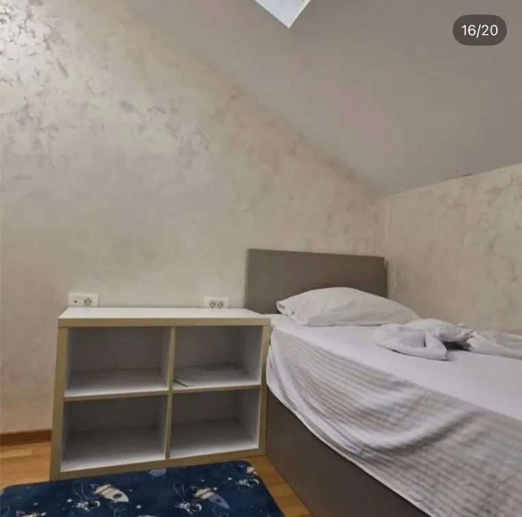 Small bedroom with a bed and a low shelving unit under the sloped ceiling.