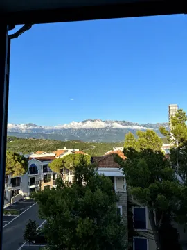 Pogled sa prozora na okolne zgrade i planine u daljini. - image 9