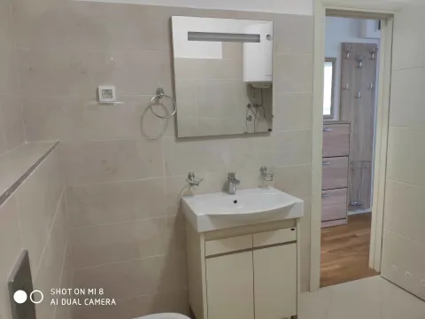 Bright bathroom with a sink, mirror, and a view of the hallway. - image 9
