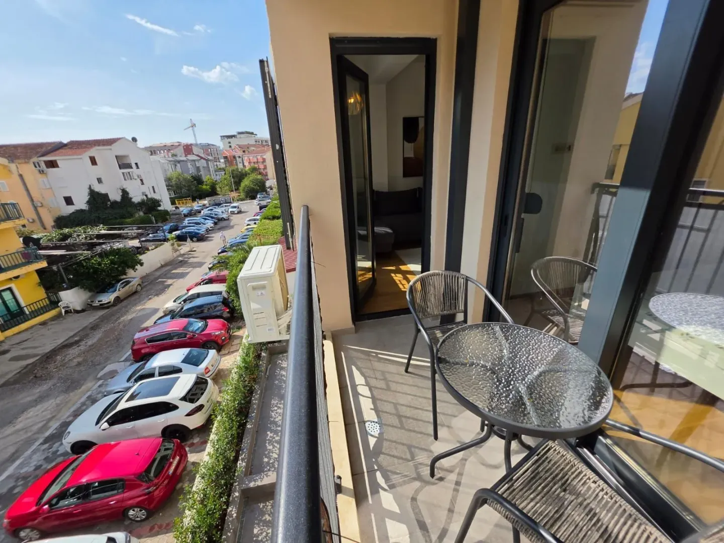 Manji namješteni balkon sa garniturom za sjedenje i pogledom na ulicu.