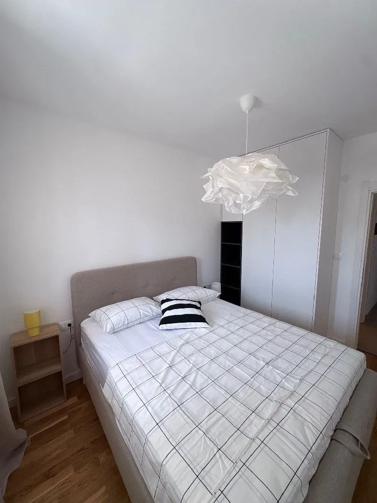 Furnished bedroom with a double bed, white wardrobe, and ceiling lighting.