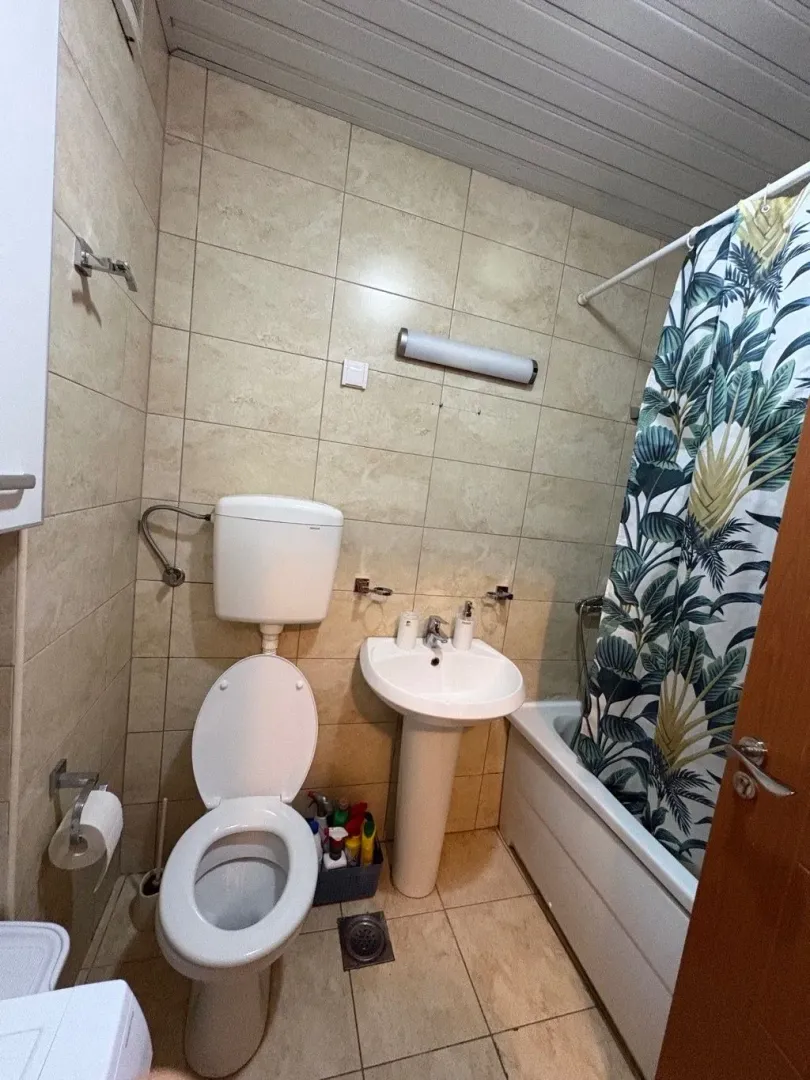Manje kupatilo sa umivaonikom, WC šoljom i kadom sa zavjesom.