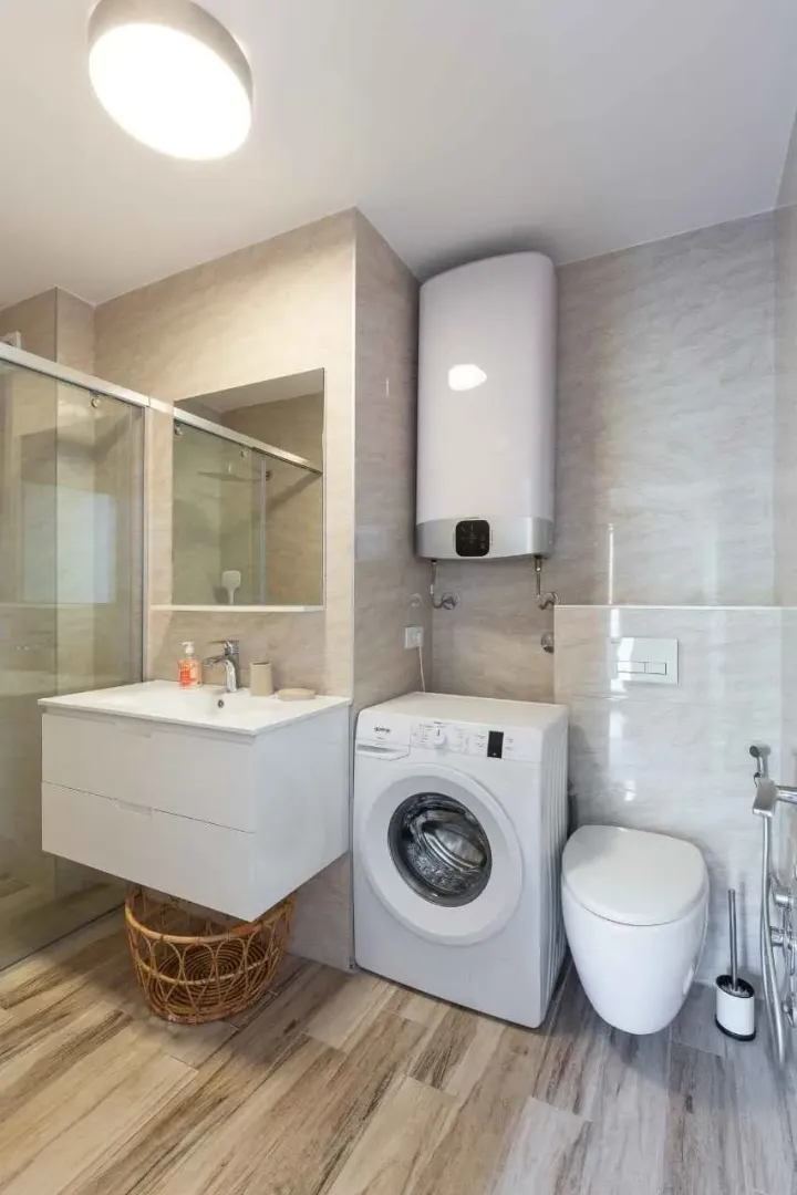 Modernly equipped bathroom with a shower cabin, washbasin, washing machine, and water heater.