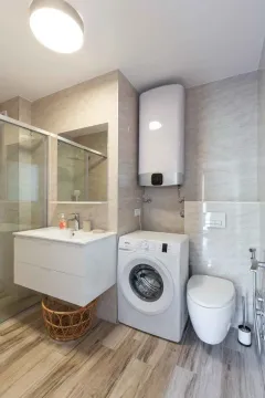 Modernly equipped bathroom with a shower cabin, washbasin, washing machine, and water heater. - image 15