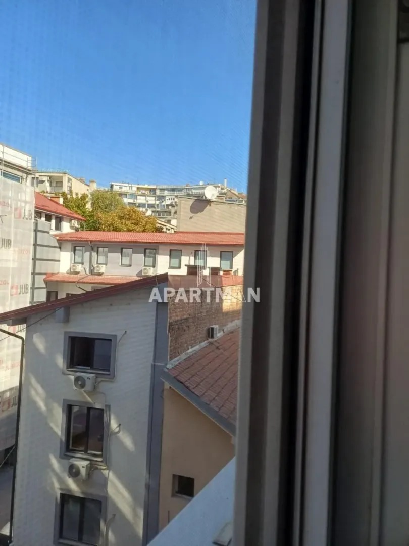 Pogled kroz prozor na okolne zgrade i gradsko naselje.