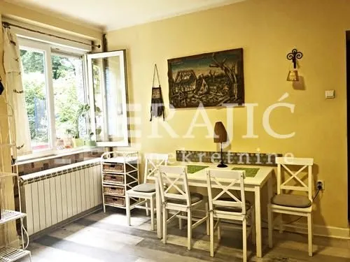 Living room with a dining table, window, and an artwork on the wall.