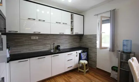 Moderna kuhinja sa bijelim elementima i tamnom radnom površinom. - image 6