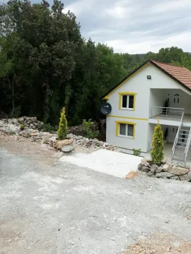 Dvospratna kuća sa bijelom fasadom i kamenim detaljima u dvorištu. - image 4
