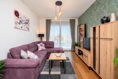 Living room with a purple sectional sofa, wooden furniture, and a TV. - image 10
