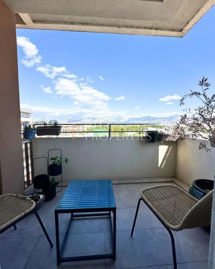 Namješten balkon sa stolom, stolicama i pogledom na okolinu.
