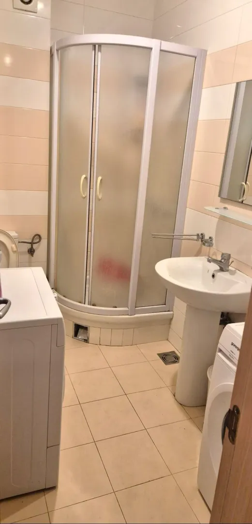 Manje kupatilo sa tuš kabinom, umivaonikom i veš mašinom.