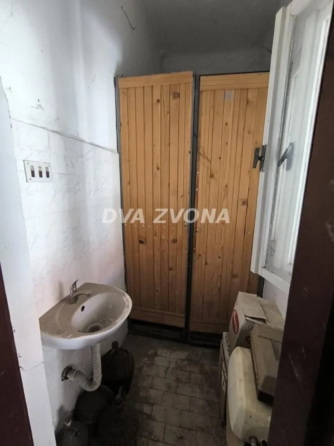 Manje kupatilo sa umivaonikom i drvenim ormarićem.