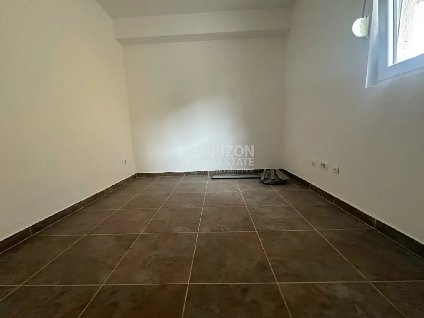 Empty room with ceramic floor tiles and white walls.