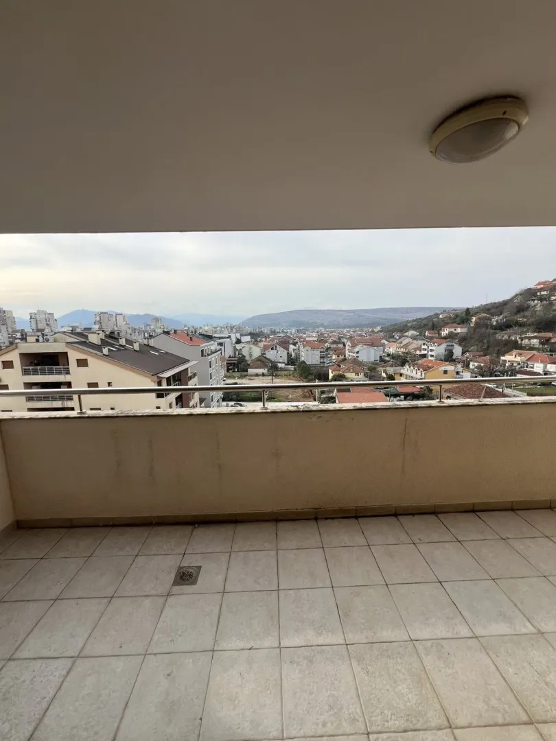 Spacious balcony with a view of the city and surrounding hills.