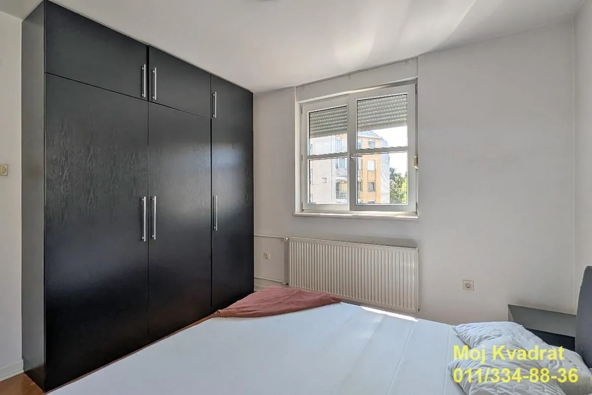 Bedroom with a double bed, a large dark wardrobe, and a window.