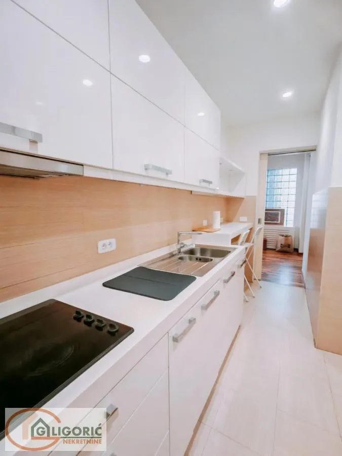 Modern white kitchen with built-in cooktop and sink.