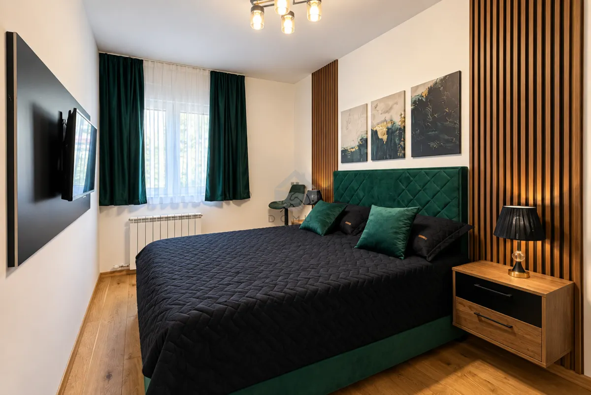 Modern bedroom with a double bed, wooden wall panels and a TV.