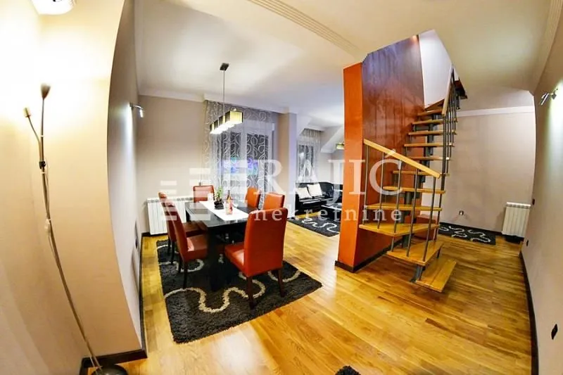 Living room with dining area and a staircase leading to the upper floor.