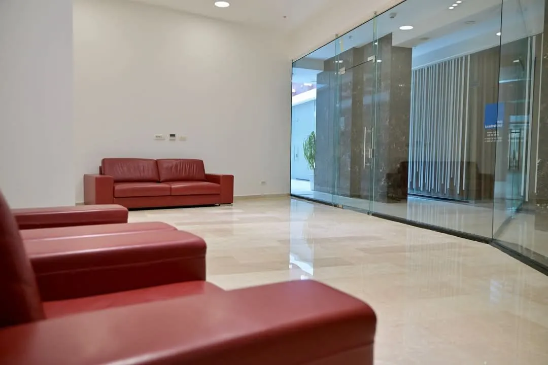 Spacious living room with red leather sofas and light flooring.