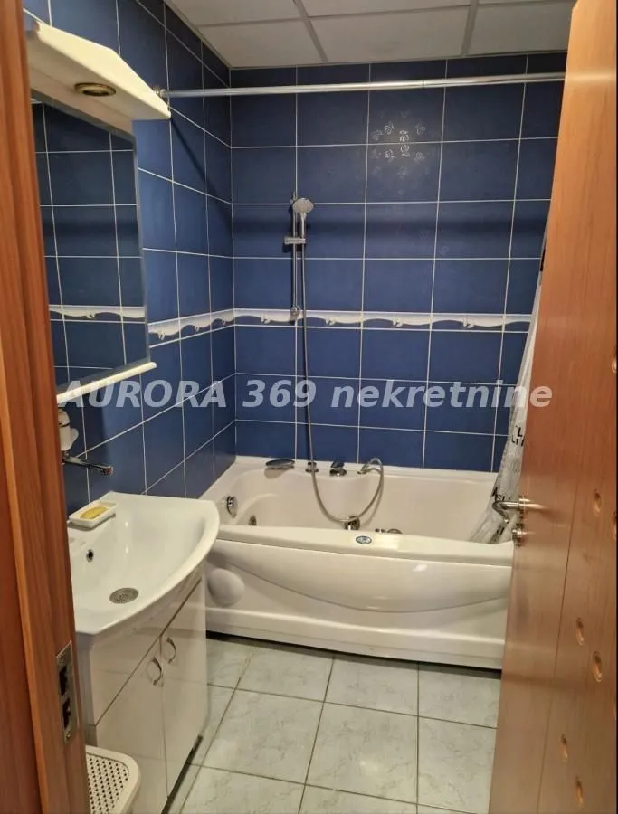 Bathroom equipped with a bathtub, a washbasin, and blue wall tiles.