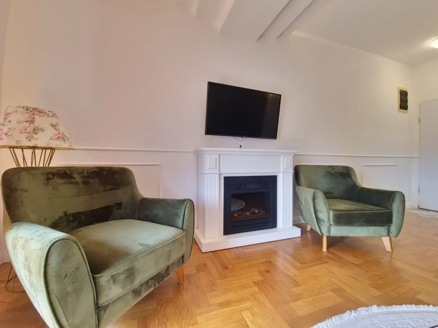 Living room with a fireplace and two green armchairs.