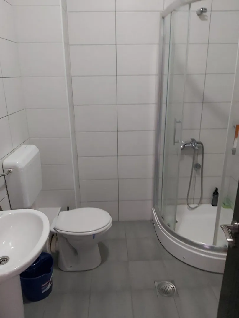 Jednostavno kupatilo sa tuš kabinom, WC šoljom i umivaonikom.