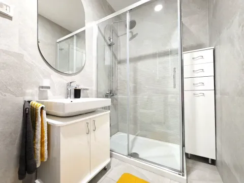 Modern bathroom with a shower cabin, washbasin, and white cabinet. - image 13