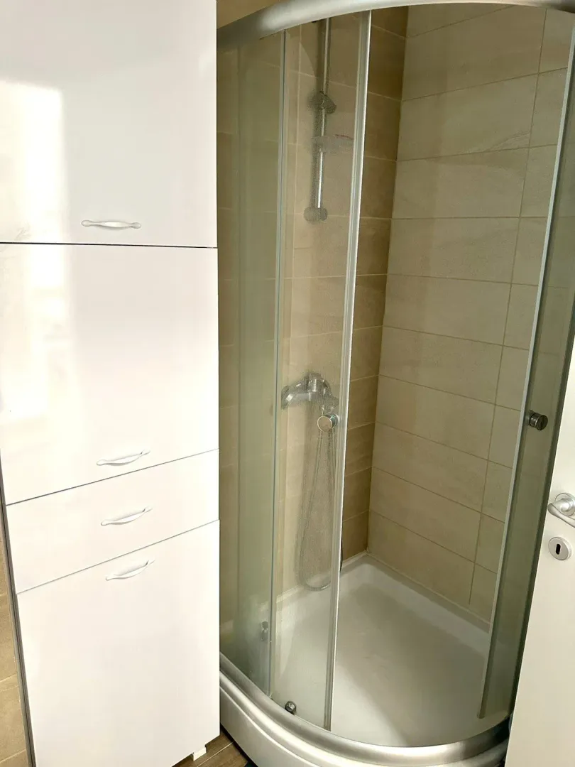 Small bathroom with a shower cabin and a white cabinet.