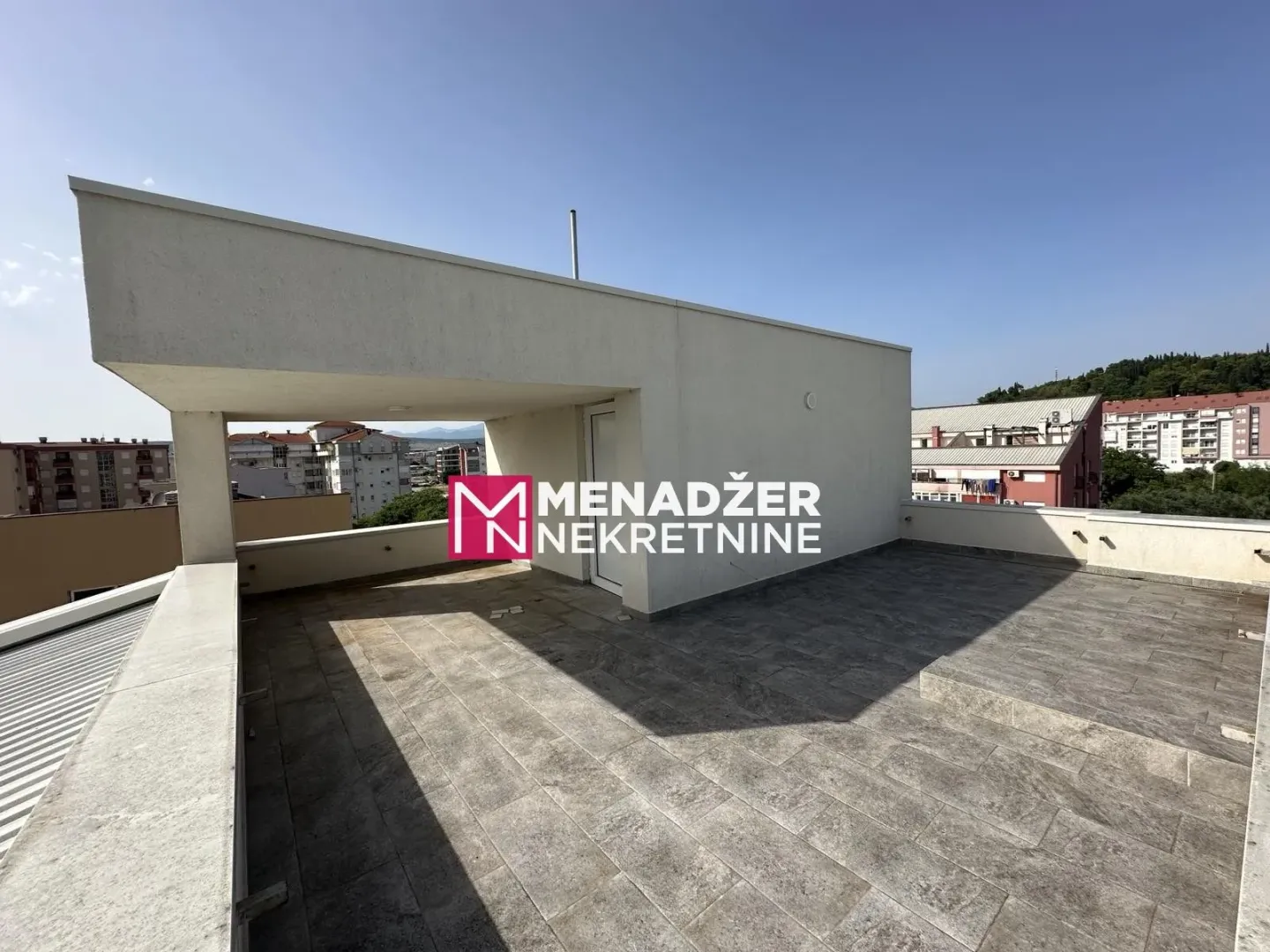 Large tiled roof terrace with a city view.