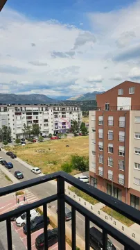 Pogled sa terase na okolne zgrade, parking i planine u daljini. - image 5