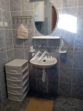 Manje kupatilo sa umivaonikom, ogledalom i pločicama na zidovima. - image 10