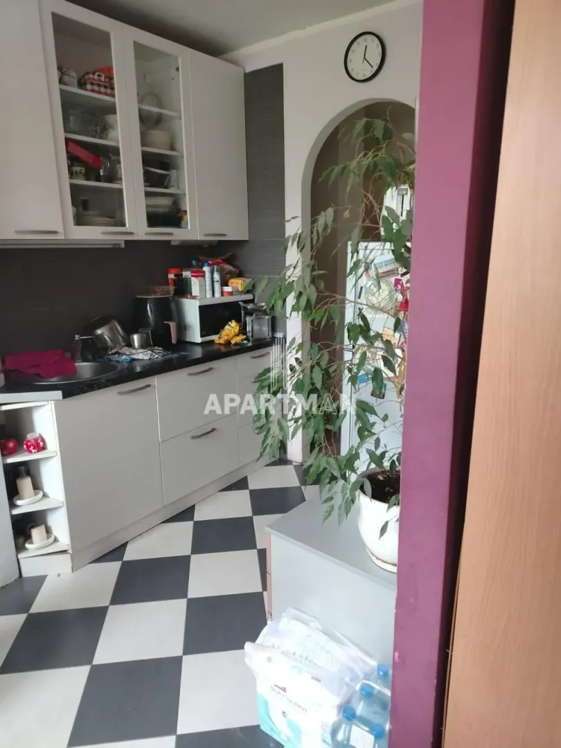 Kuhinja sa belim elementima i crno-belim keramičkim pločicama na podu.