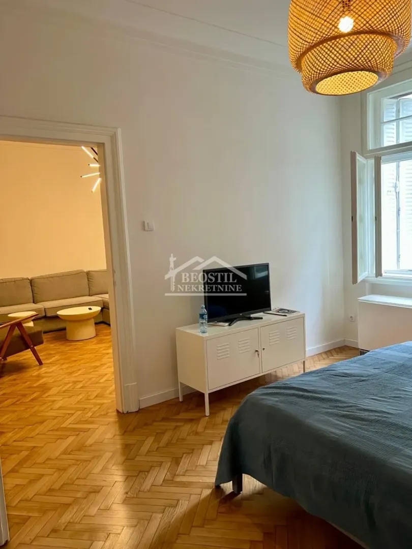 Bedroom with a bed, TV cabinet, and a view of the adjacent room.