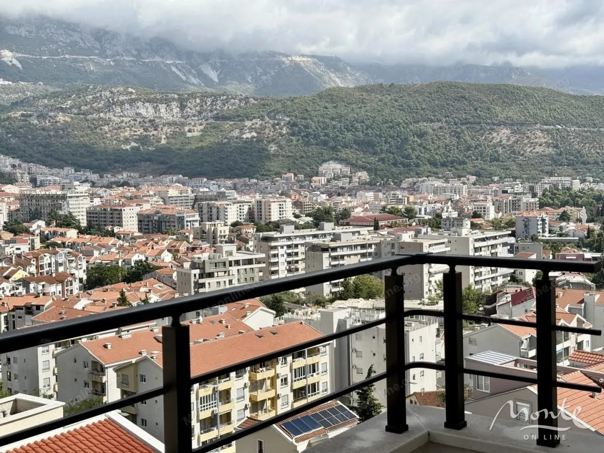 Pogled sa terase na grad i planine u pozadini.