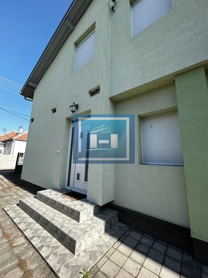 Pogled na ulaz i fasadu kuće sa popločanim stepeništem.