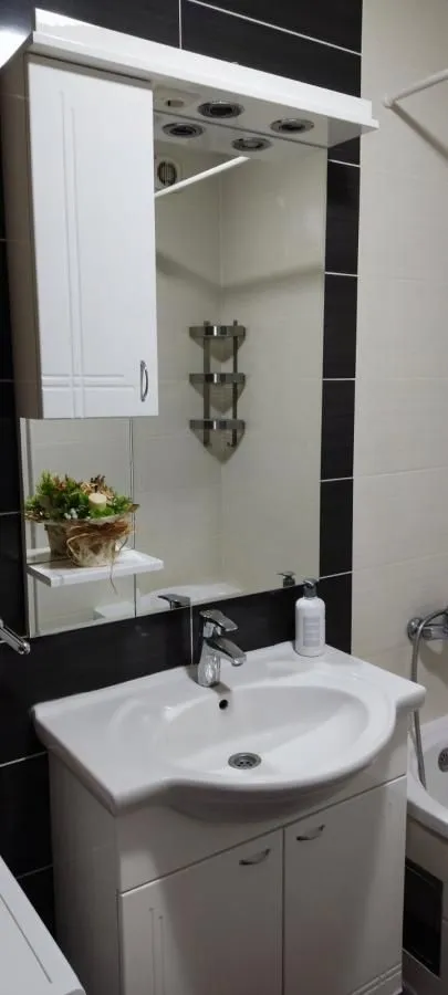 Kupatilo sa umivaonikom, ormarićem sa ogledalom i pločicama u kontrastnim bojama.