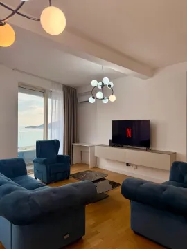 Dnevna soba sa plavim foteljama, sofom, televizorom i pogledom na more. - image 7