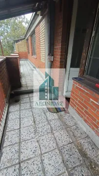 Dugački popločani balkon sa zidom od cigle i ulaznim vratima. - image 9