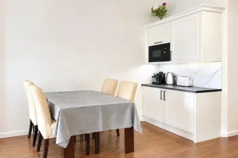 White kitchen with a dining table and chairs. - image 5