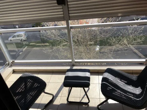 Balcony with two black wicker chairs and a small table. - image 19