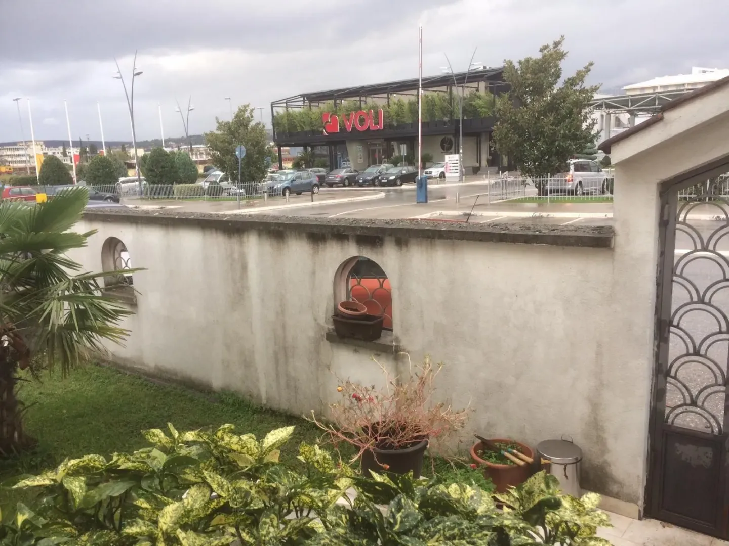 Dvorište sa betonskom ogradom i kapijom.