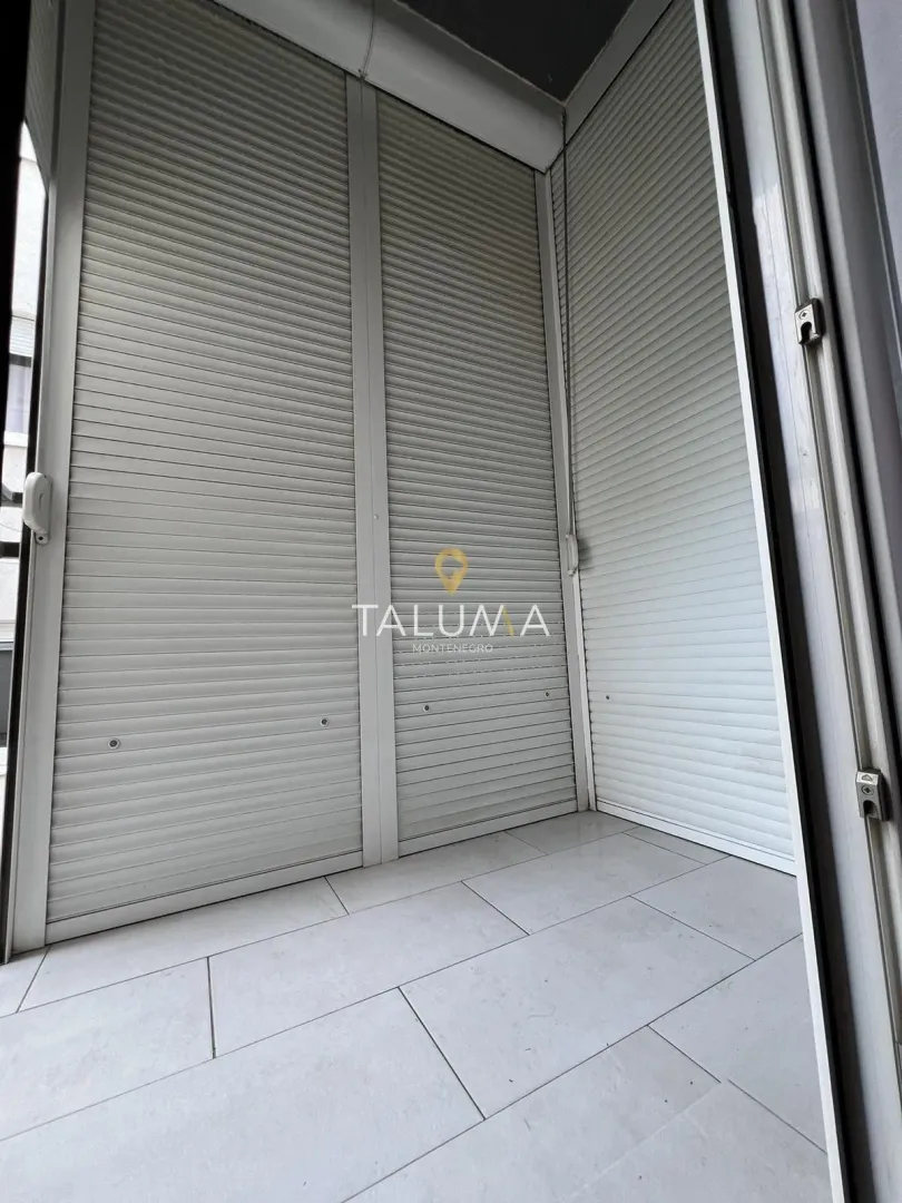 Natkriveni balkon sa spuštenim roletnama i pločicama na podu.