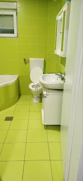 Kupatilo obloženo zelenim pločicama sa kadom, umivaonikom i toaletom. - image 4