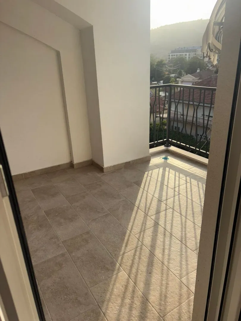 Nenamješten balkon sa popločanim podom i pogledom na okolinu.