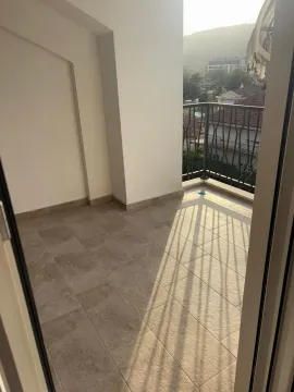 Nenamješten balkon sa popločanim podom i pogledom na okolinu. - image 3