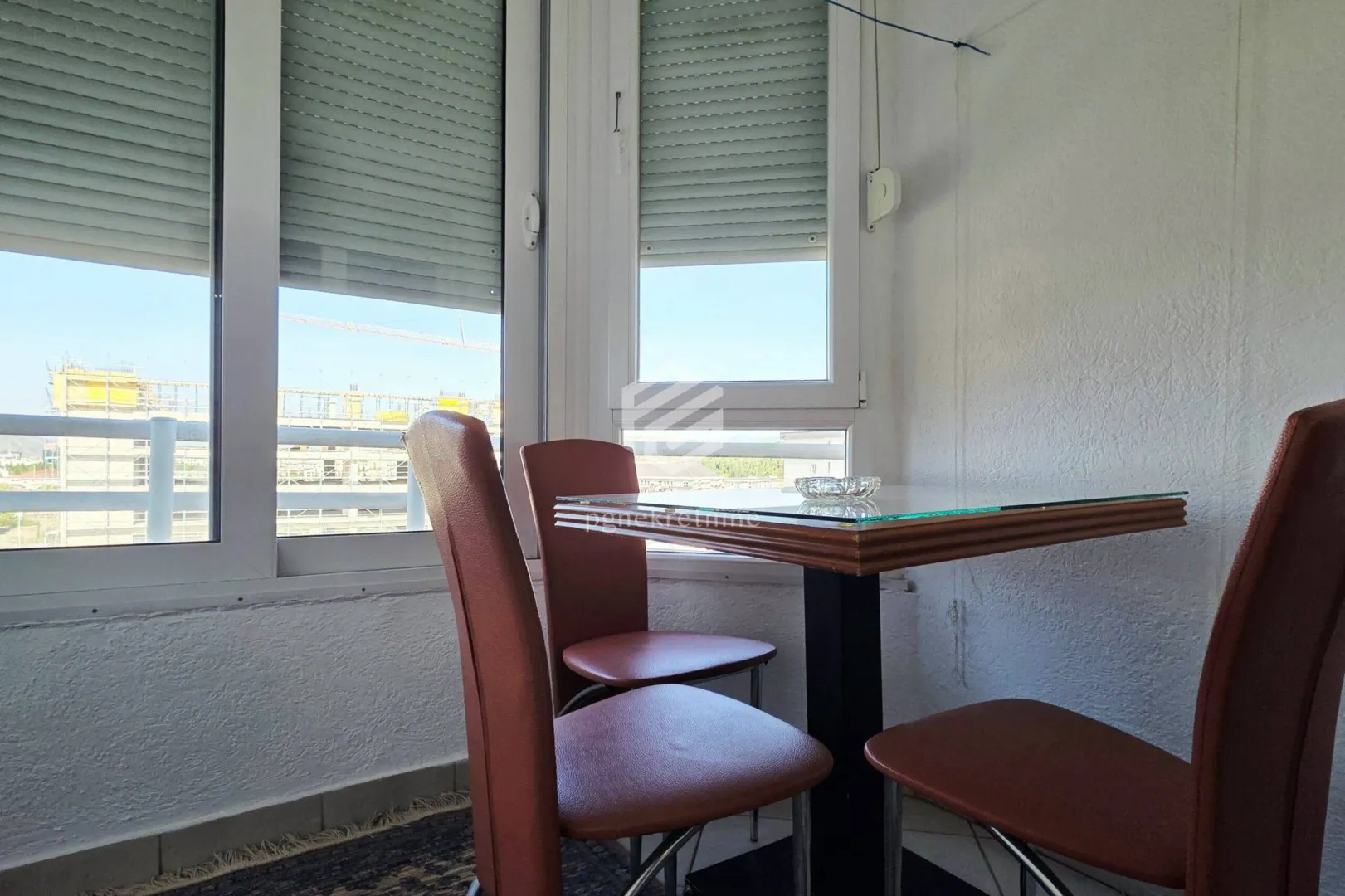 Enclosed balcony with a dining table and chairs by the windows.